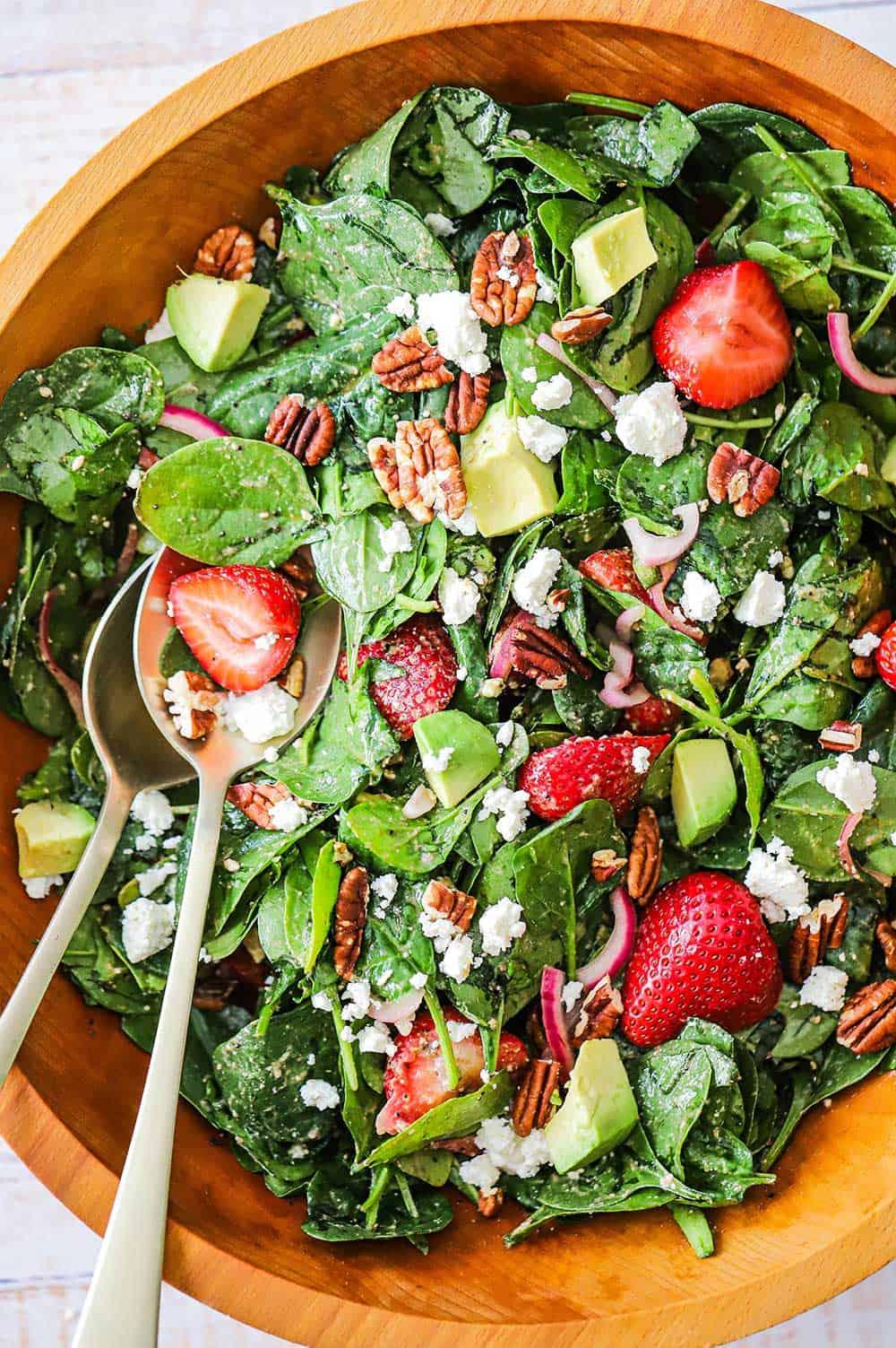 overhead shot of a beautifully arranged strawberry spinach salad on a wooden table