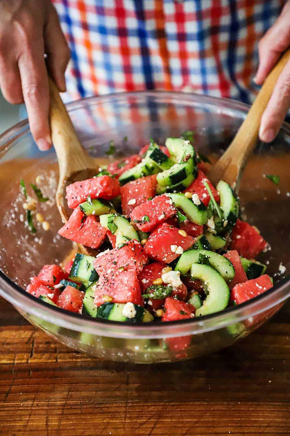 a person tossing the Watermelon Cucumber Pasta Salad in a bowl