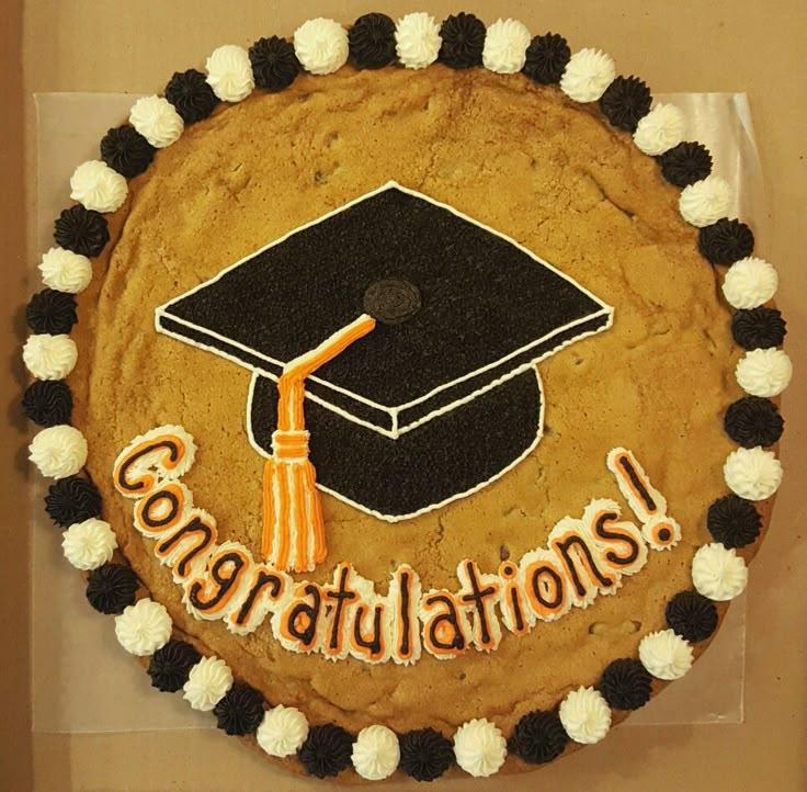 a beautifully decorated, large round cookie cake with 'Congrats Grad!' written in frosting, surrounded by graduation-themed decorations like caps and diplomas
