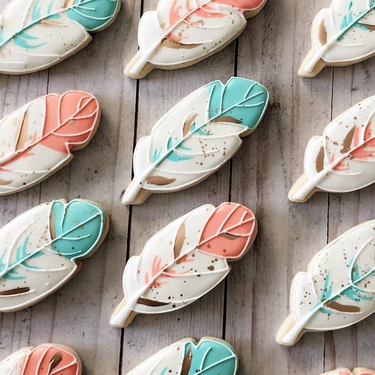 feather-shaped cookies arranged on a rustic wooden table with a cup of tea