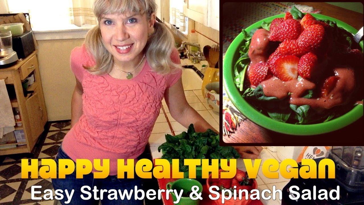 a person smiling while eating a strawberry spinach salad
