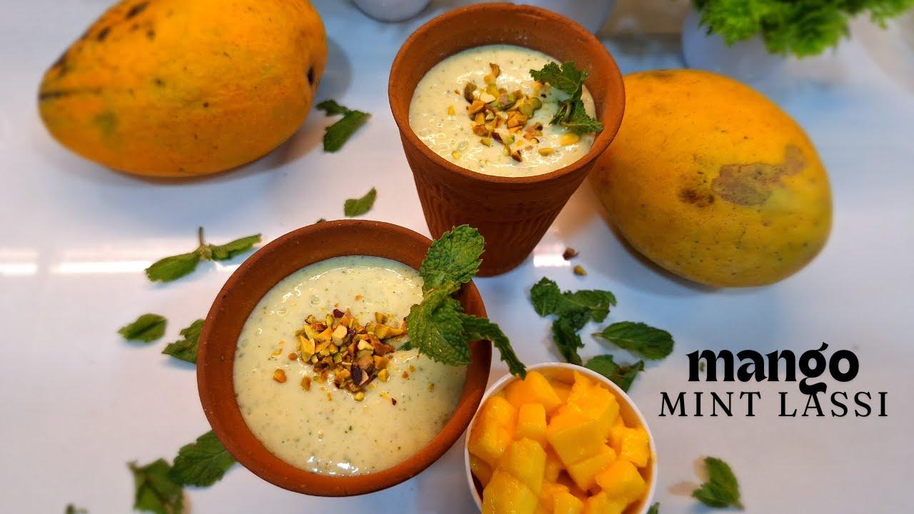 a pitcher of mint majesty lassi surrounded by fresh mangoes and mint leaves