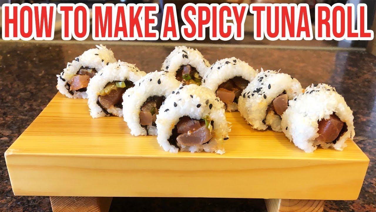 person making spicy tuna roll with a bamboo mat