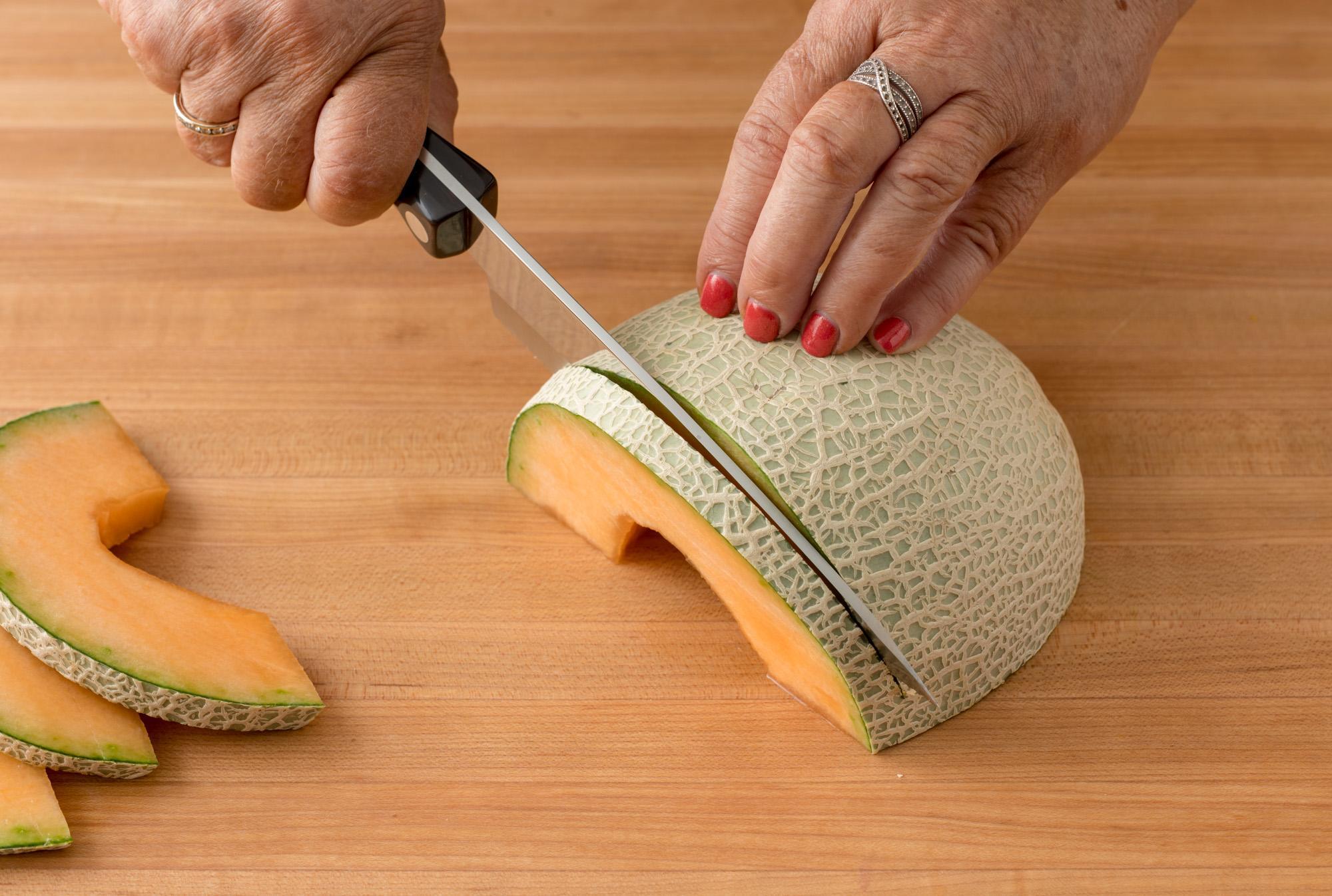 A close-up of a perfectly ripe cantaloupe, sliced open with a knife.