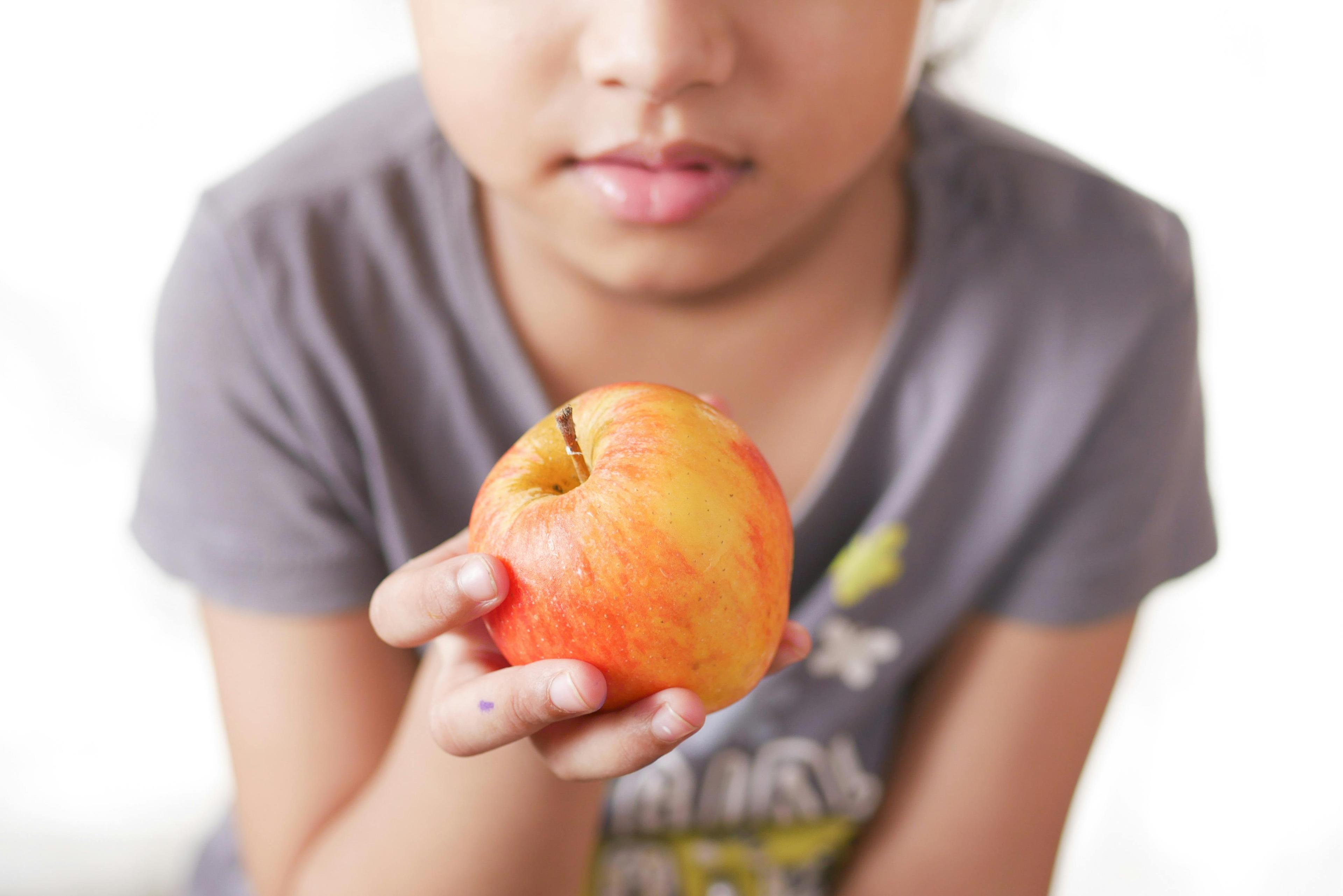 close up shot of child's hand holding a blue apple slice