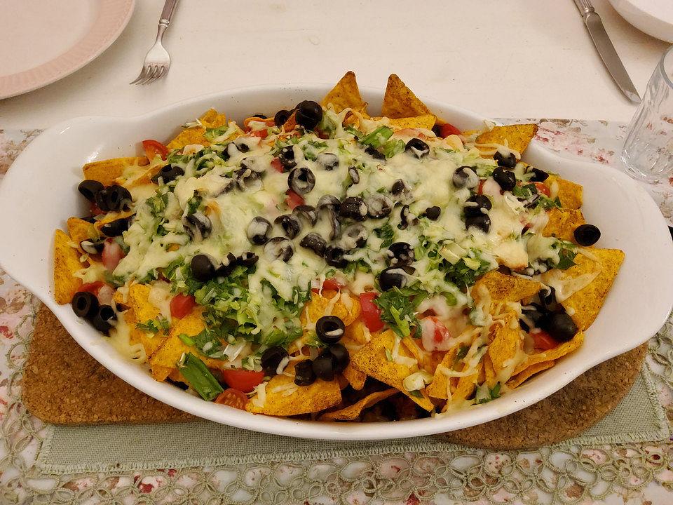 a hand sprinkling cotija cheese over mango salsa nachos supreme