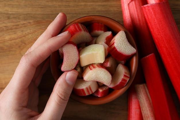 close up shot of rhubarb stalks being chopped on a wooden cutting board
