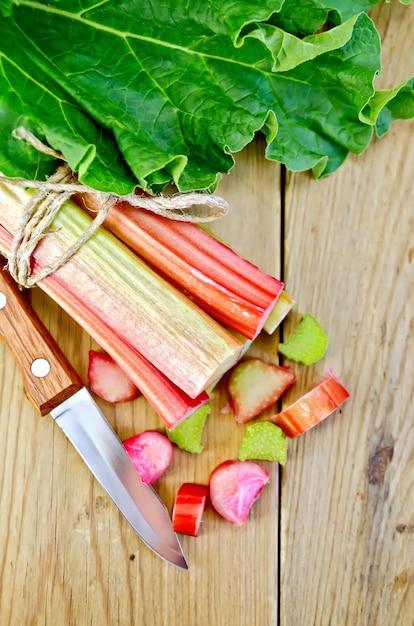 Overhead shot of rhubarb stalks being chopped on a wooden cutting board