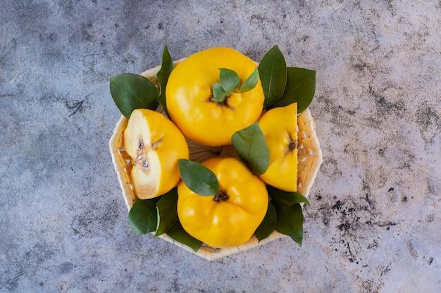 Whole and halved quinces on a wooden surface