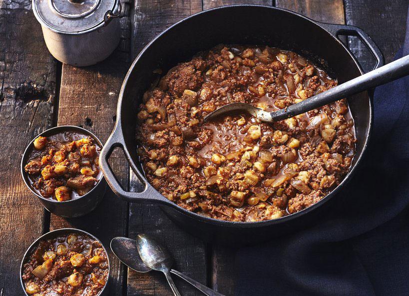 lifestyle shot of someone enjoying sweet corn and chorizo chili by a cozy fireplace