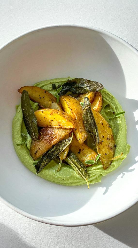 Close-up shot of tender-crisp vegetables coated in sage-butter sauce, served in a rustic bowl