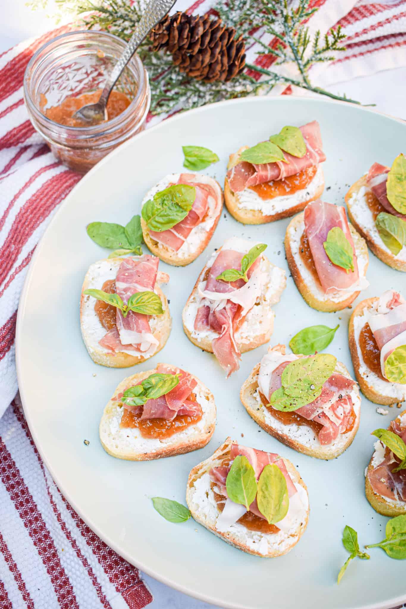 overhead shot of goat cheese and fig jam crostini arranged on a picnic blanket