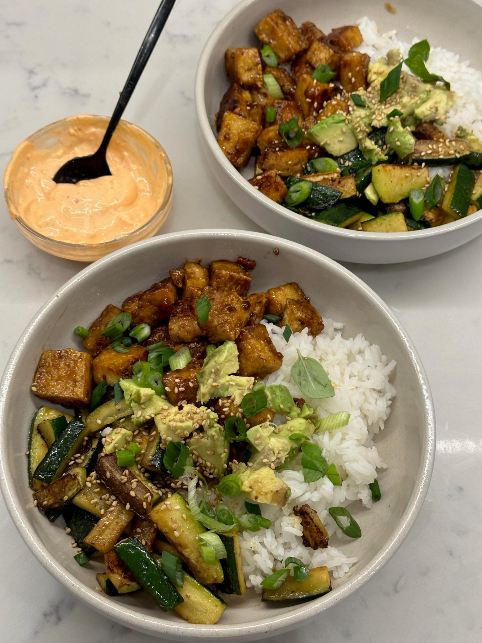 a tofu and zucchini bowl being served with a side of steamed rice