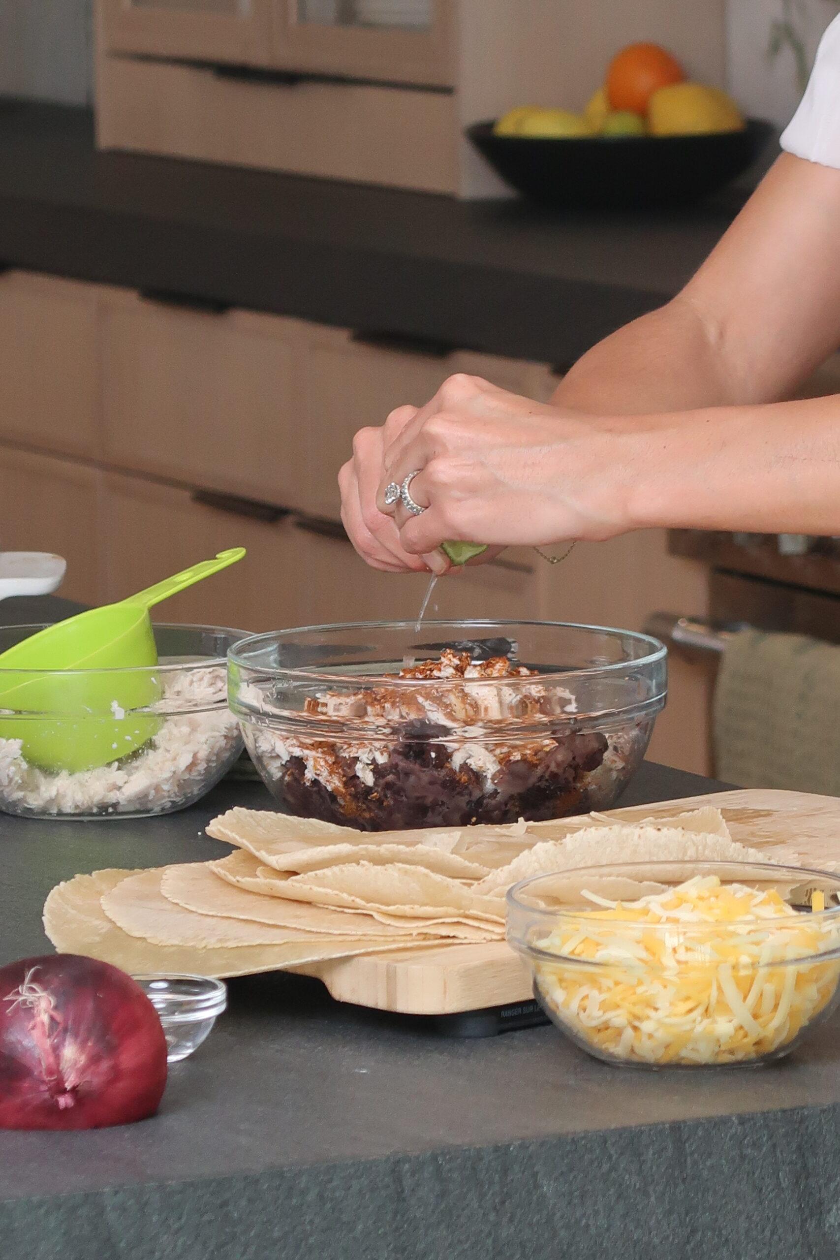 a person adding toppings to a chicken enchilada protein bowl