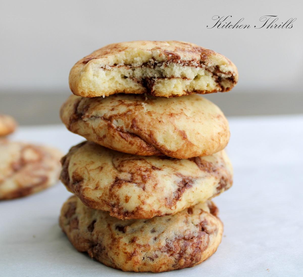 Someone taking a bite of a Nutella swirled hazelnut cookie