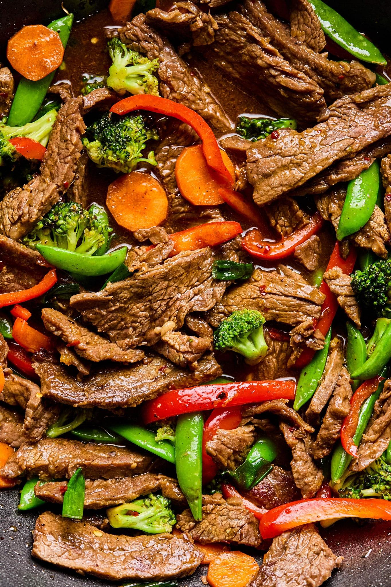 close-up of vegetables being stir-fried in a wok with balsamic glaze