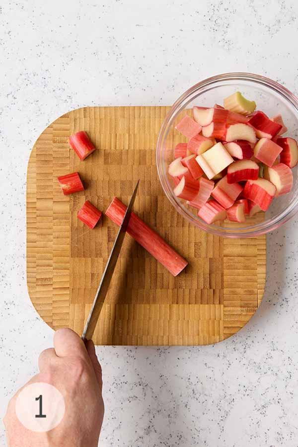 overhead shot of rhubarb stalks being chopped on a wooden cutting board