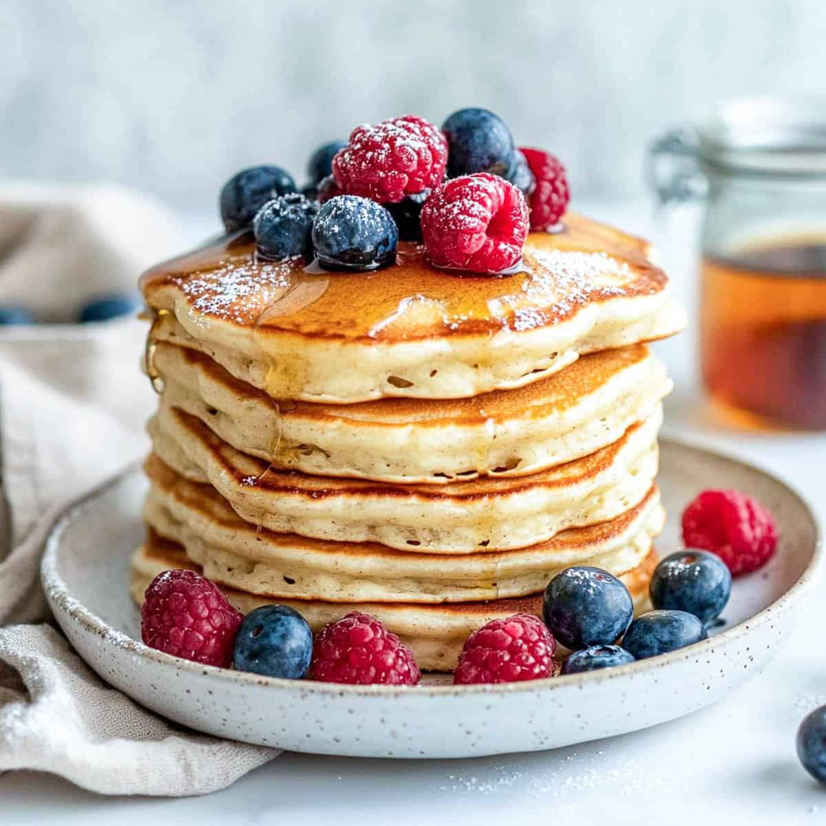 stack of cottage cheese protein pancakes with fresh berries and syrup