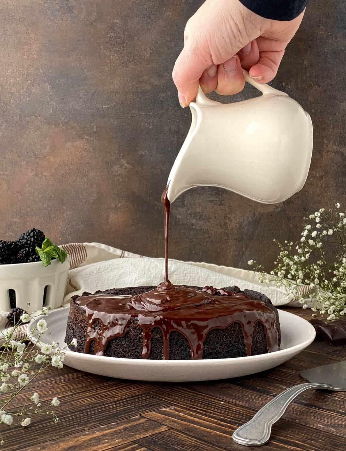 A close-up of the chocolate ganache being poured over the top layer of the cake