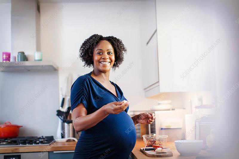 pregnant woman happily preparing food in the kitchen