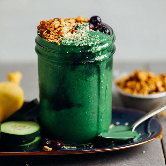 vibrant green spirulina smoothie in a glass with fresh fruit