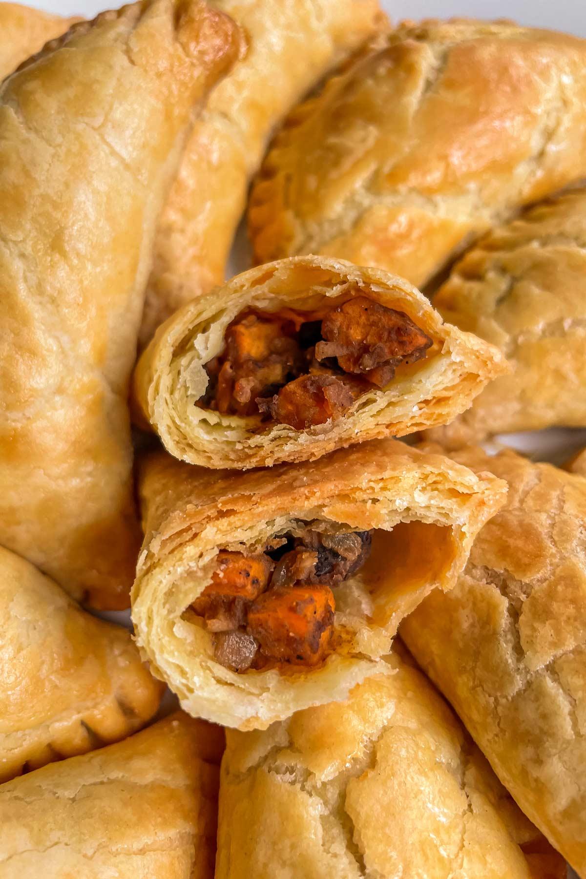 close-up shot of a golden-brown sweet potato and black bean empanada being cut open