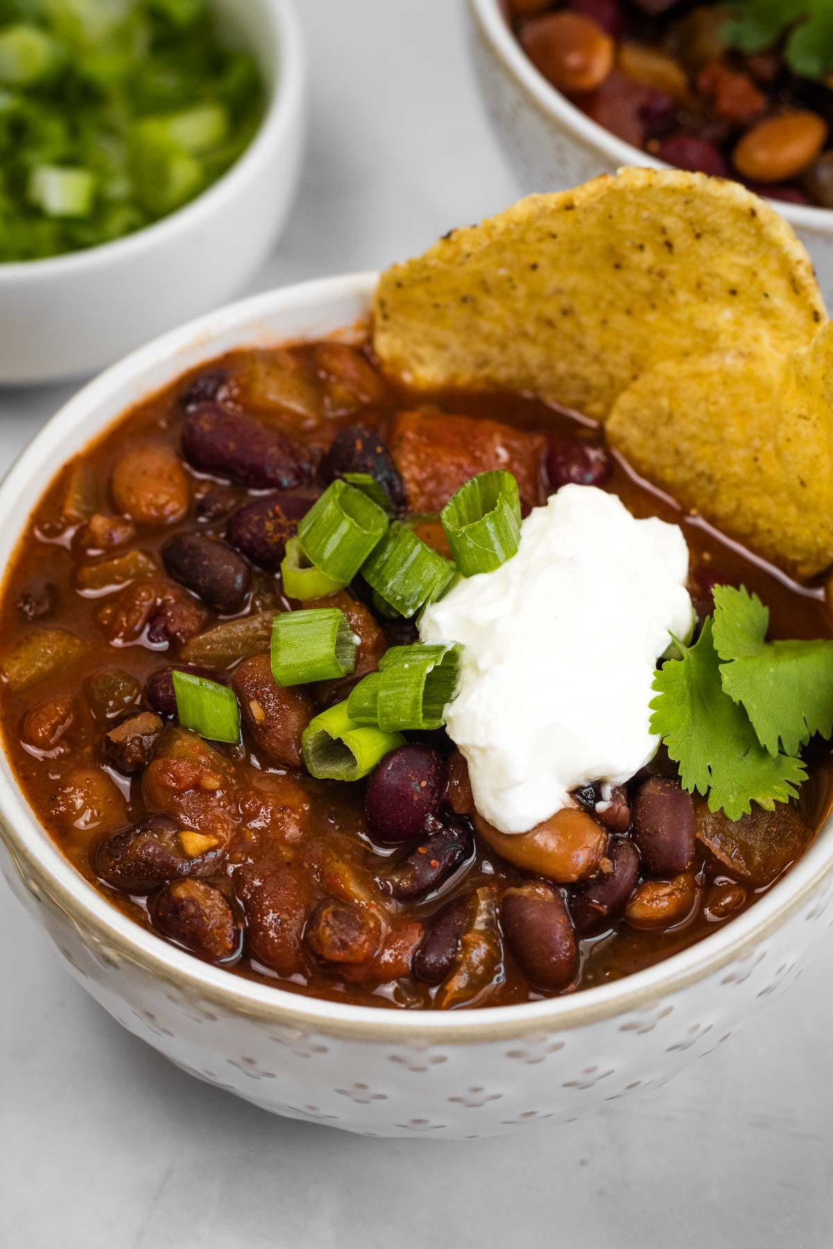 Close-up shot of a bowl of cranberry bean and sausage chili garnished with cheese and cilantro