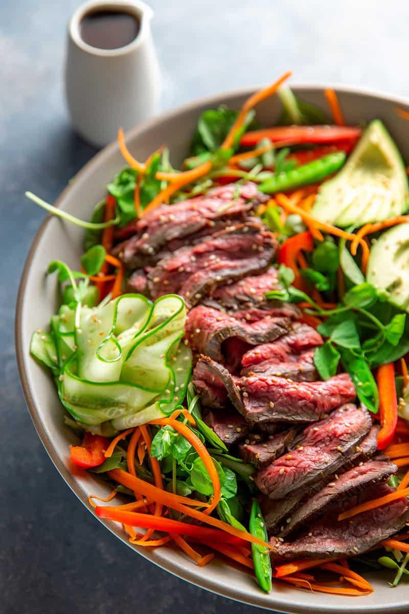 Overhead shot of a colorful steak salad with various vegetables and toppings
