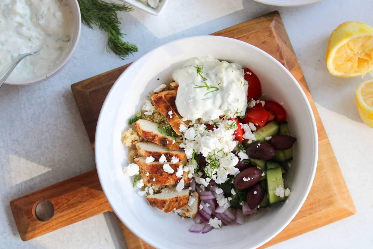 Greek chicken quinoa bowl with lemon wedges and feta cheese