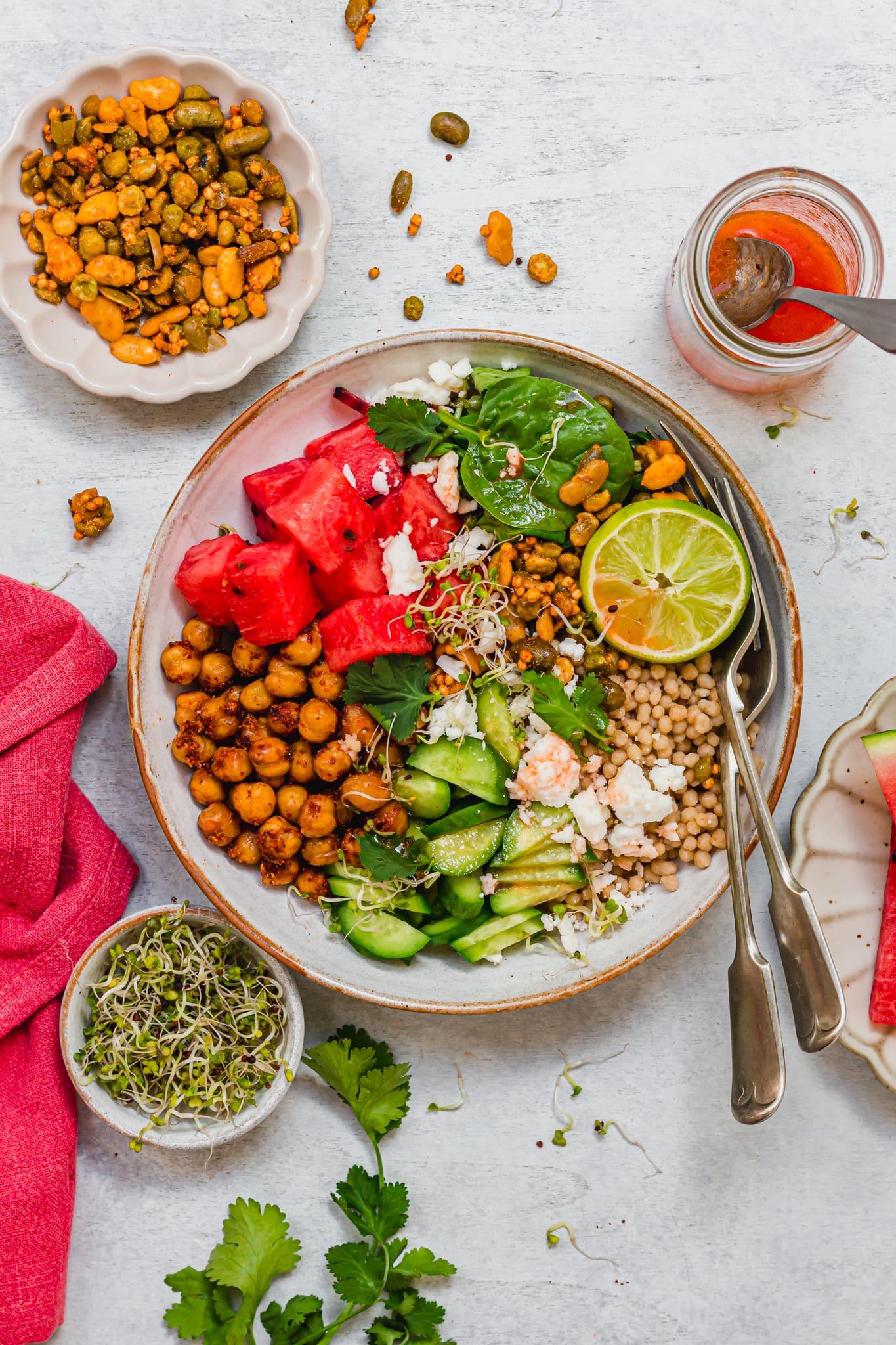 bowl of watermelon and chickpea salad drizzled with tahini dressing