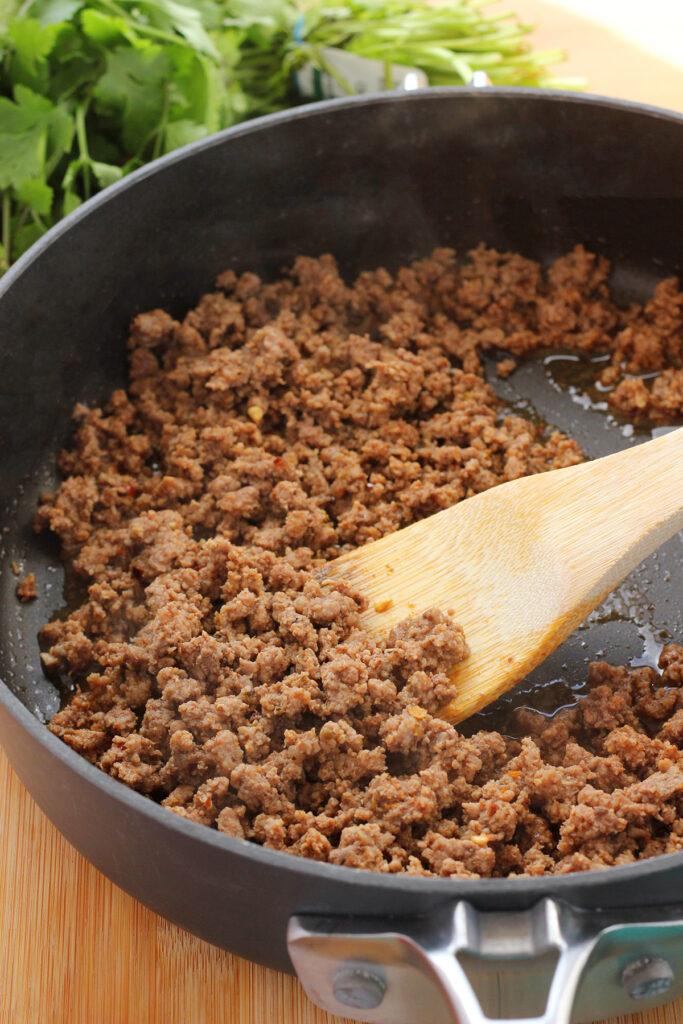 close up of taco meat sizzling in a pan