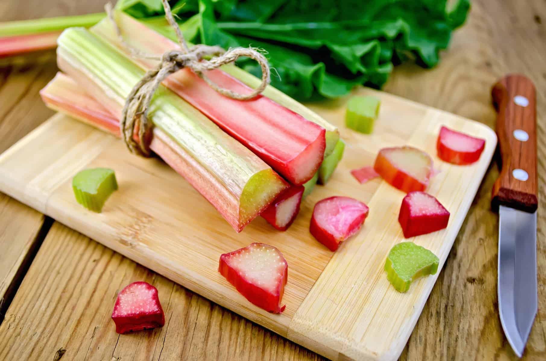 Hands cutting Rhubarb Ginger Snap Bars into squares on a wooden cutting board