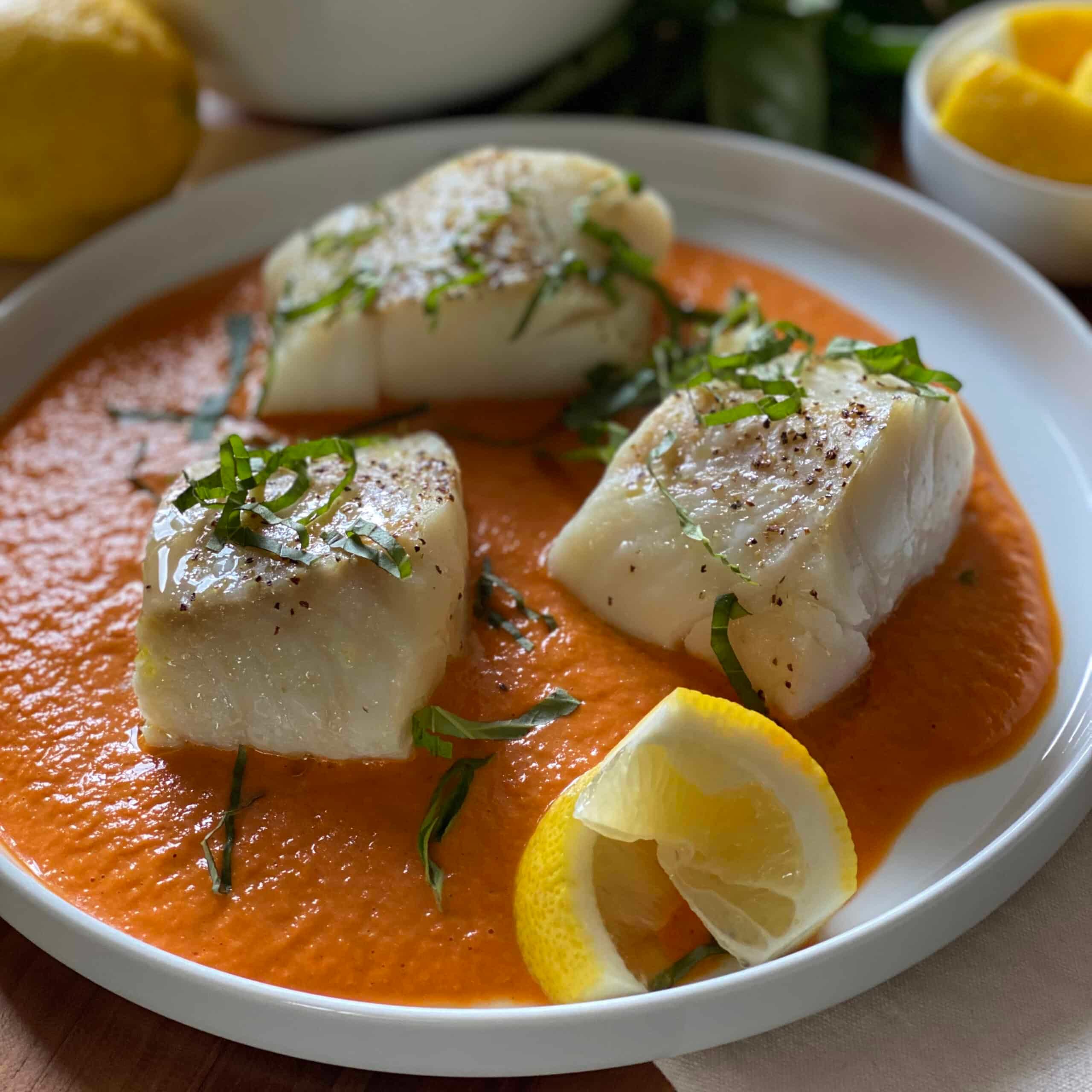 A close up shot of grilled cod with roasted red pepper sauce being drizzled on it