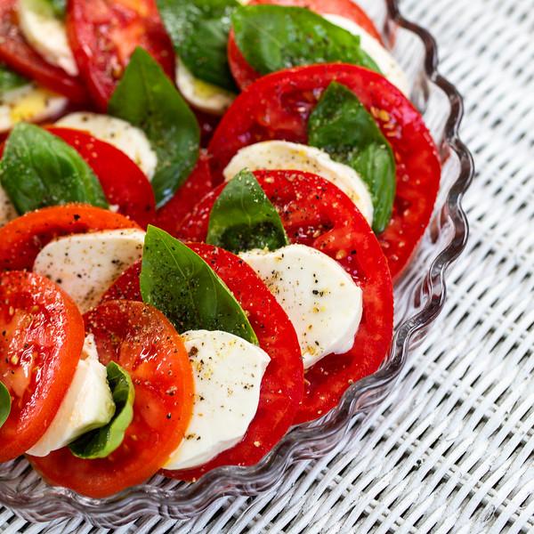 close up of sliced tomatoes and mozzarella with basil leaves