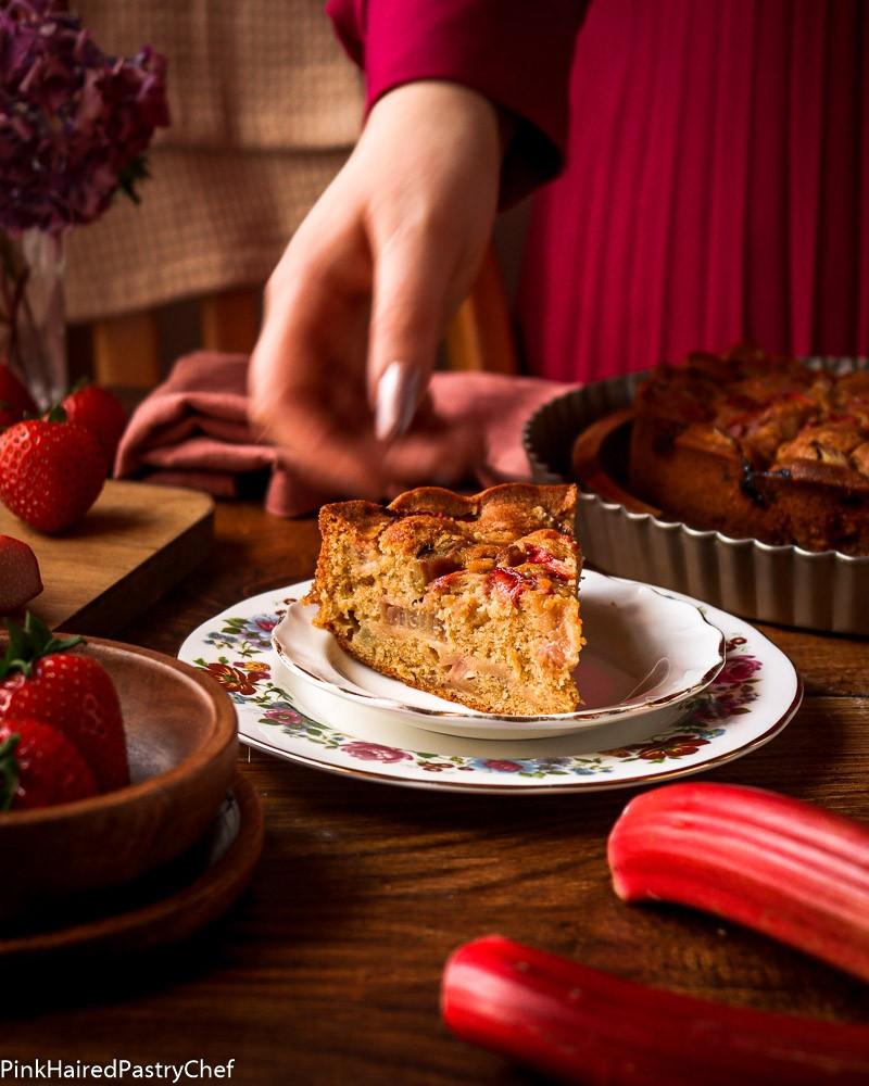 woman smiling, holding a freshly baked raspberry rhubarb cake
