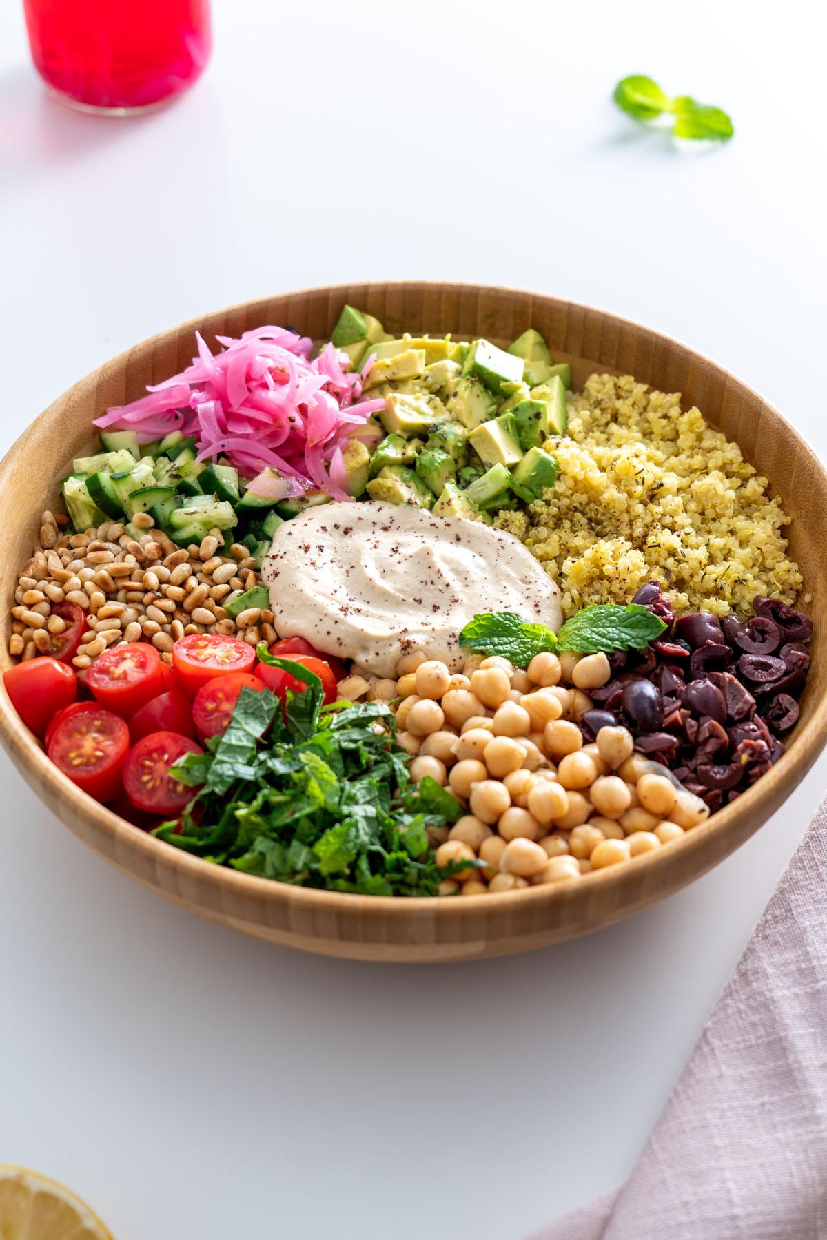 overhead shot of a beautifully arranged quinoa salad with roasted vegetables on a wooden table