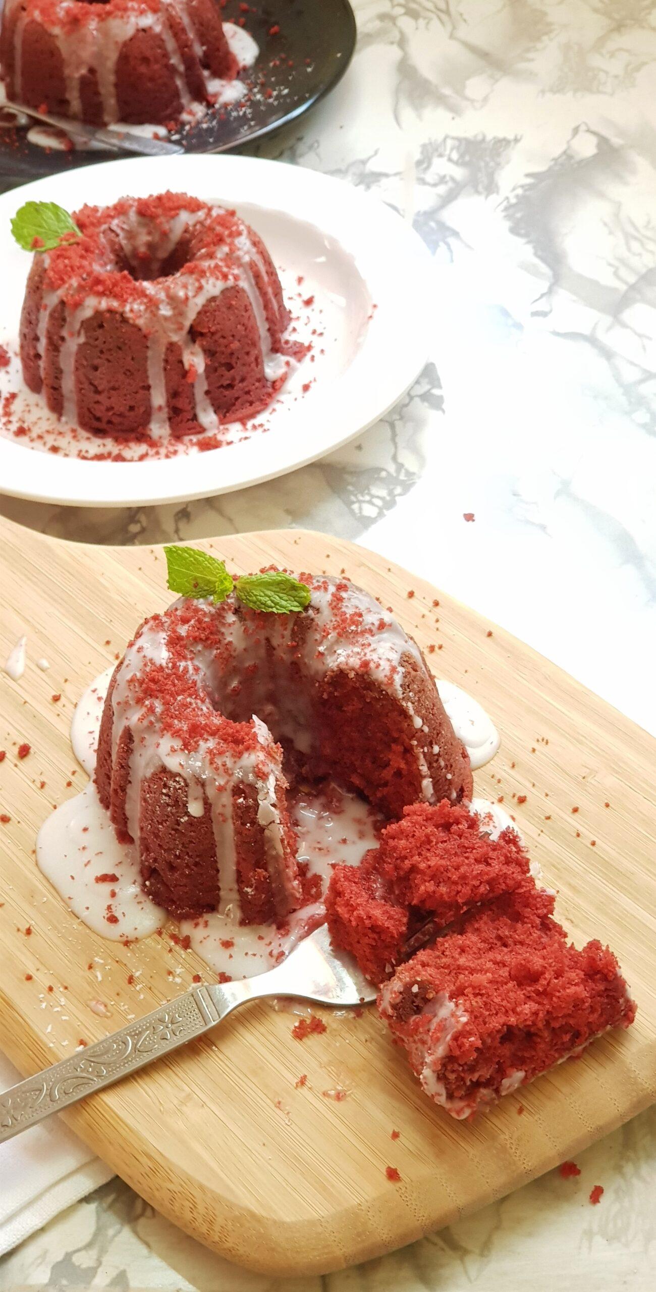 a hand sprinkling powdered sugar on a red velvet cake