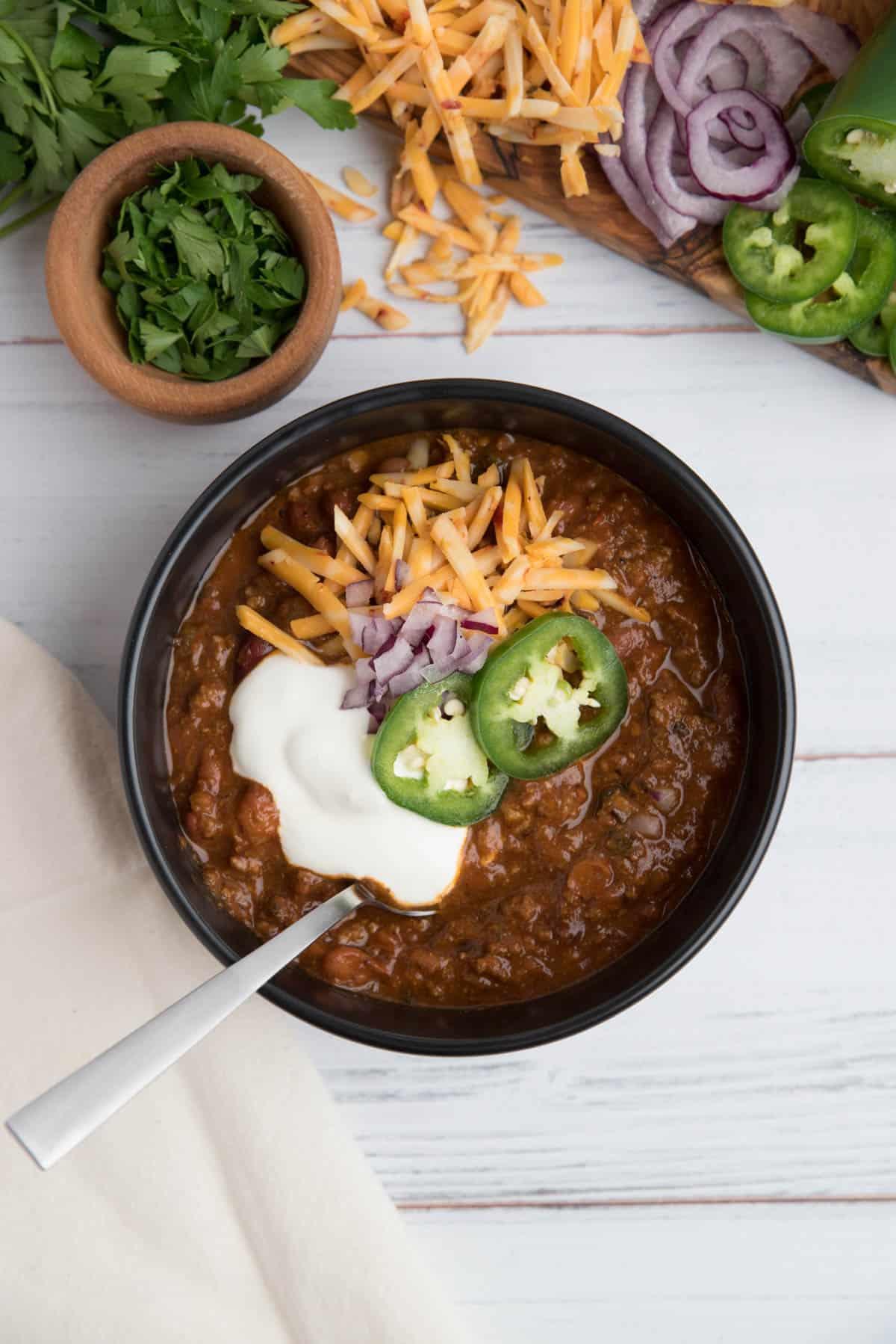 bowl of chocolate chili garnished with cilantro and a dollop of sour cream