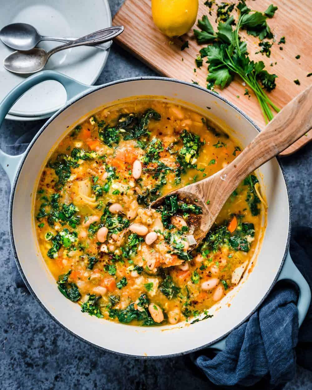 close up of pot of white bean soup with kale simmering on the stove