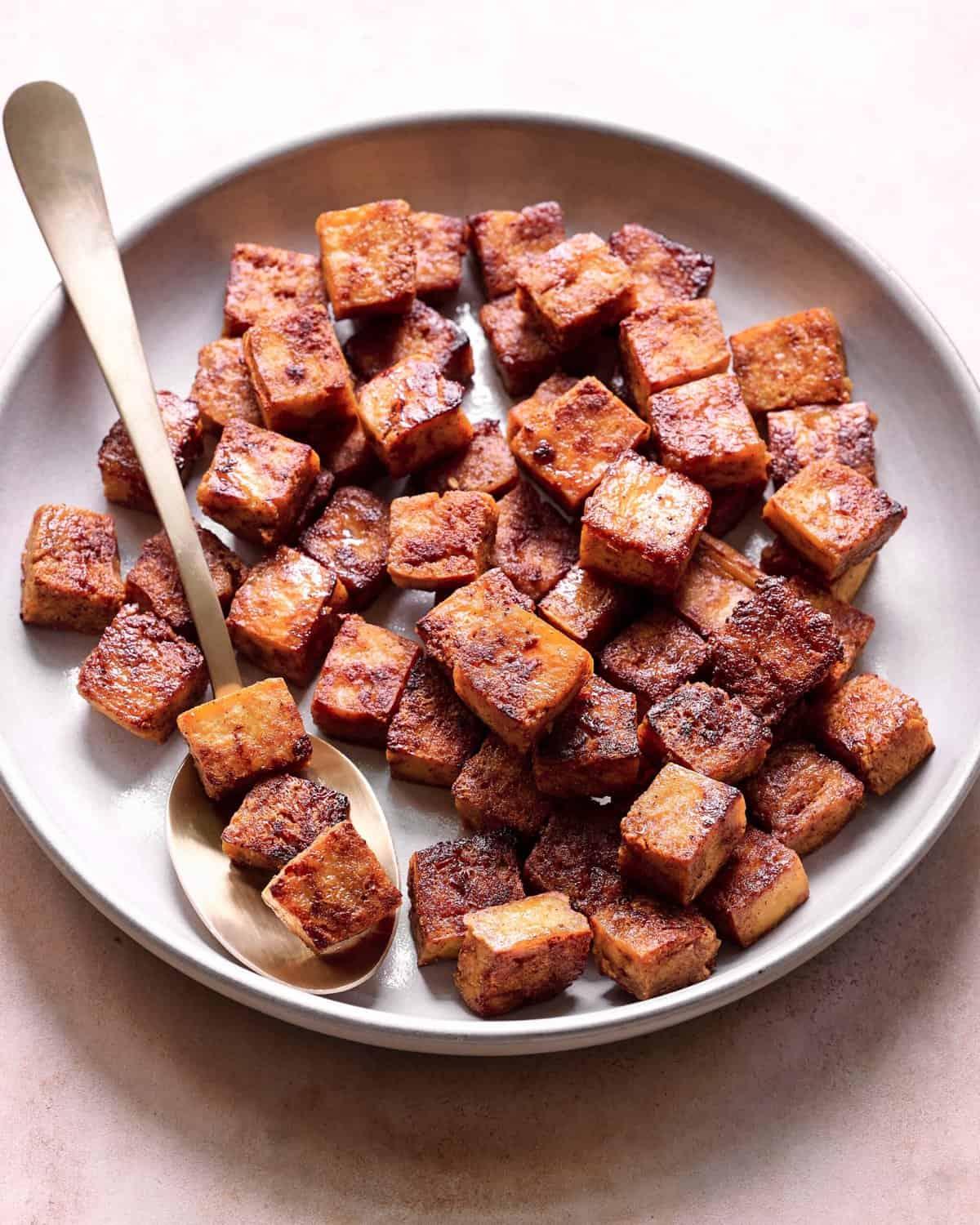 a close-up shot of tofu cubes marinating in a bowl with French herbs and spices