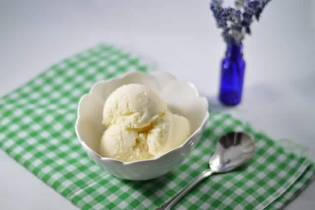 a bowl of vanilla lavender ice cream with a spoon taking a scoop out