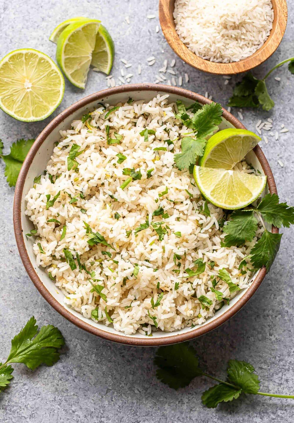 close-up shot of cilantro lime rice with lime wedges and cilantro sprigs
