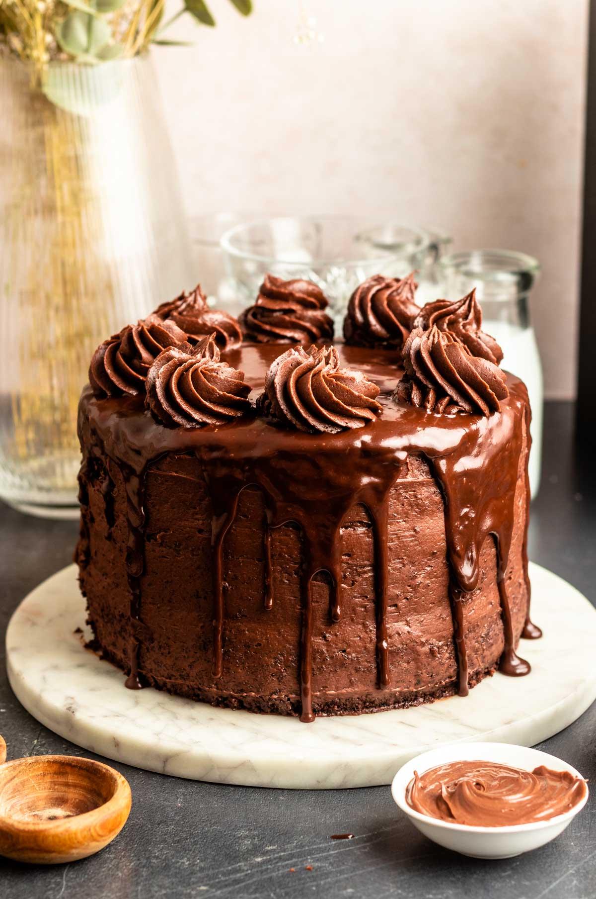 A person spreading chocolate buttercream frosting on a layer of Chocolate Nutella Swirl Layer Cake