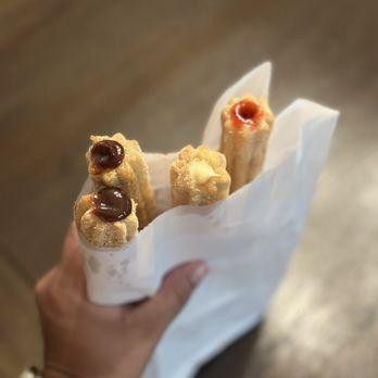 a close-up shot of freshly made spicy mango churros being held up