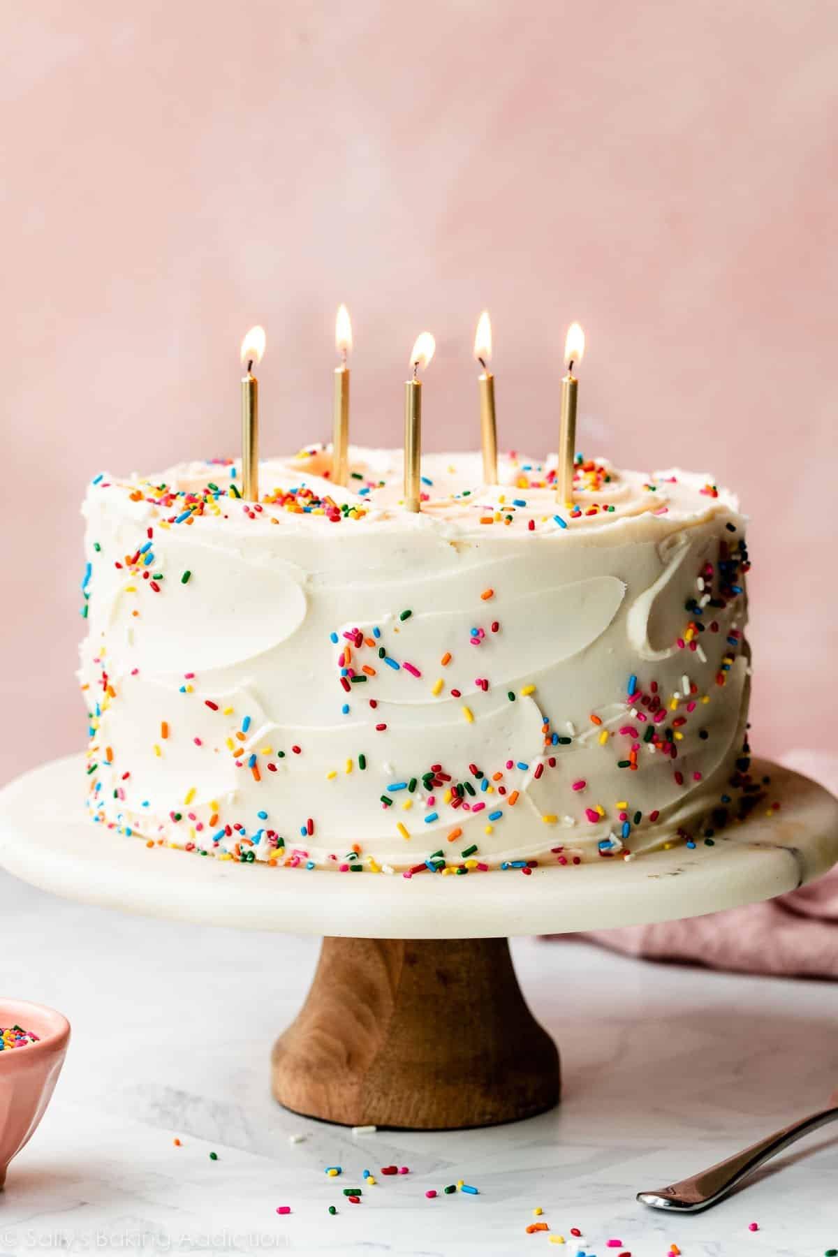 three layer celebration cake decorated with frosting and sprinkles