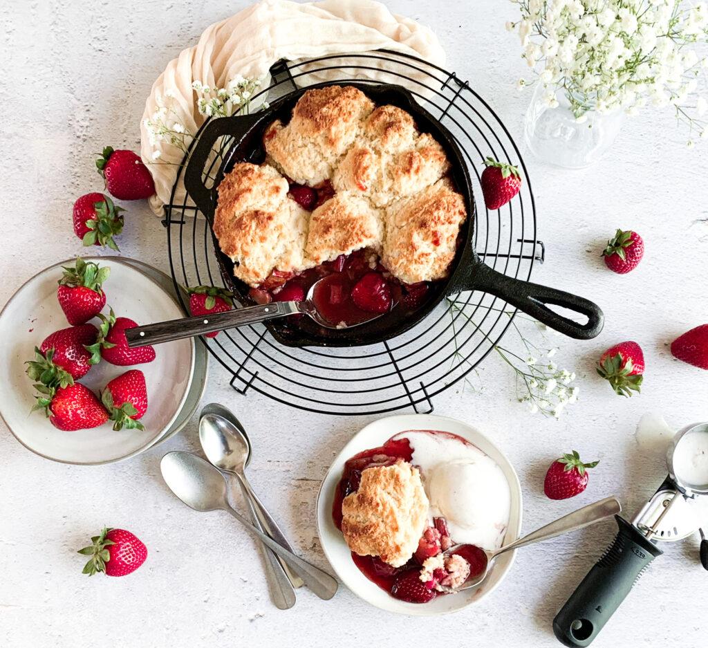 Overhead shot of Rhubarb Strawberry Shortcake Cobbler being baked in a cast iron skillet.