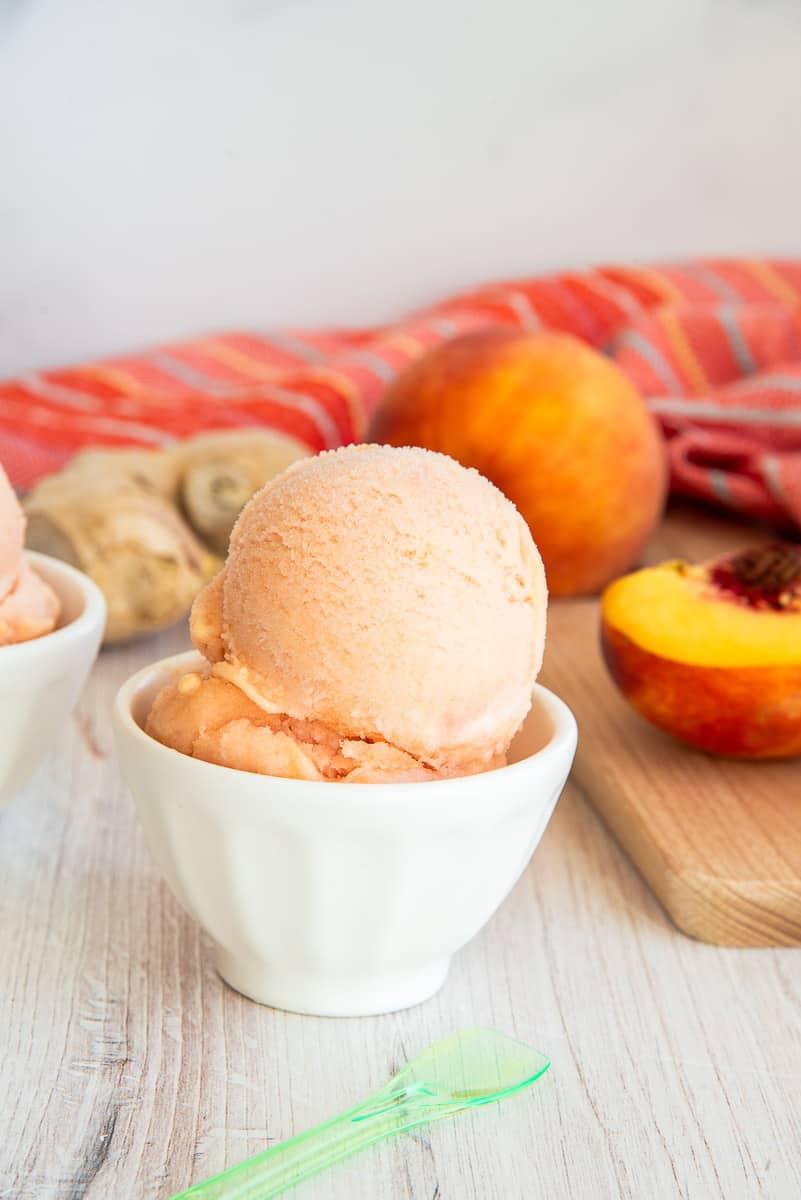 scoops of peach ginger ice cream in a glass bowl