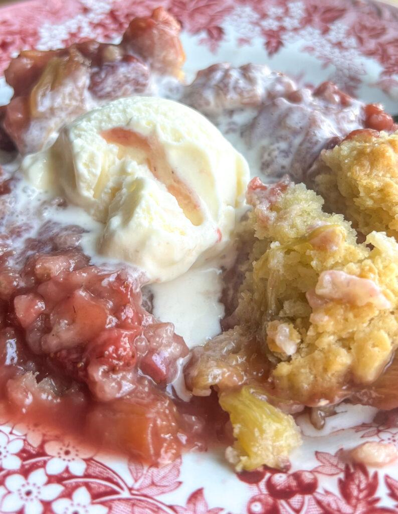 Close-up shot of a slice of Rhubarb Strawberry Shortcake Cobbler being served, with steam rising.