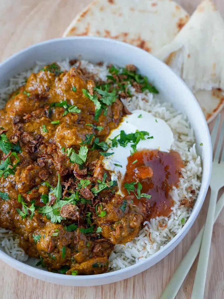 A close-up shot of grilled chicken and vegetable curry with coconut milk being prepared on a grill.