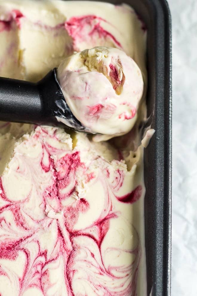 close-up of raspberry ripple ice cream being swirled in a loaf pan
